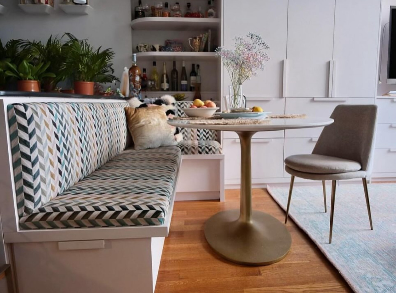 L-shaped custom banquette with herringbone upholstery and tulip dining table