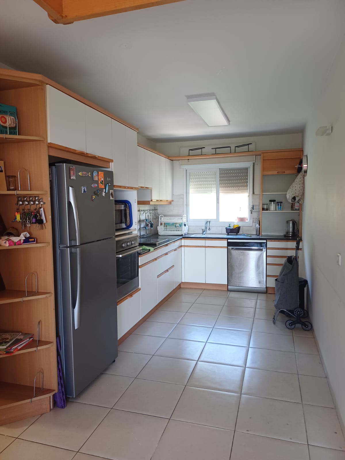 Existing galley kitchen — white cabinetry with wood trim and outdated appliance layout